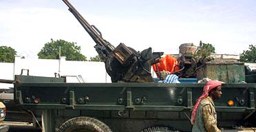 An Islamist fighter walks past an anti-aircraft machine gun seized from Abdi Awale Qaybdiid